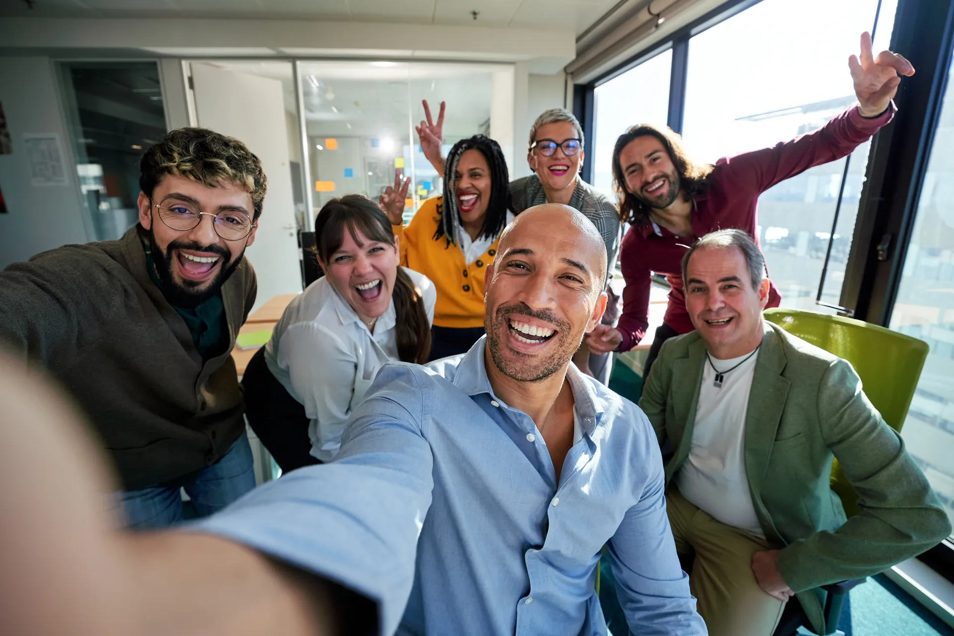 A diverse Ottri team smiling and taking a group selfie in a bright modern office